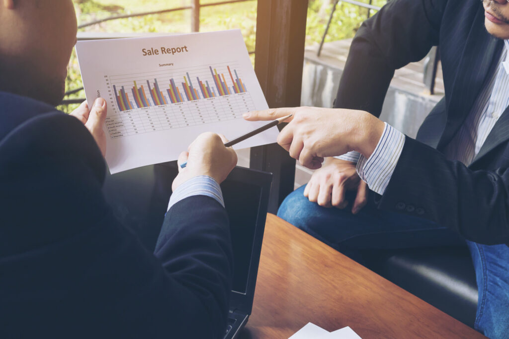 ポイント還元のデータが載ったグラフ付きレポートを見ながら話し合うビジネスマン